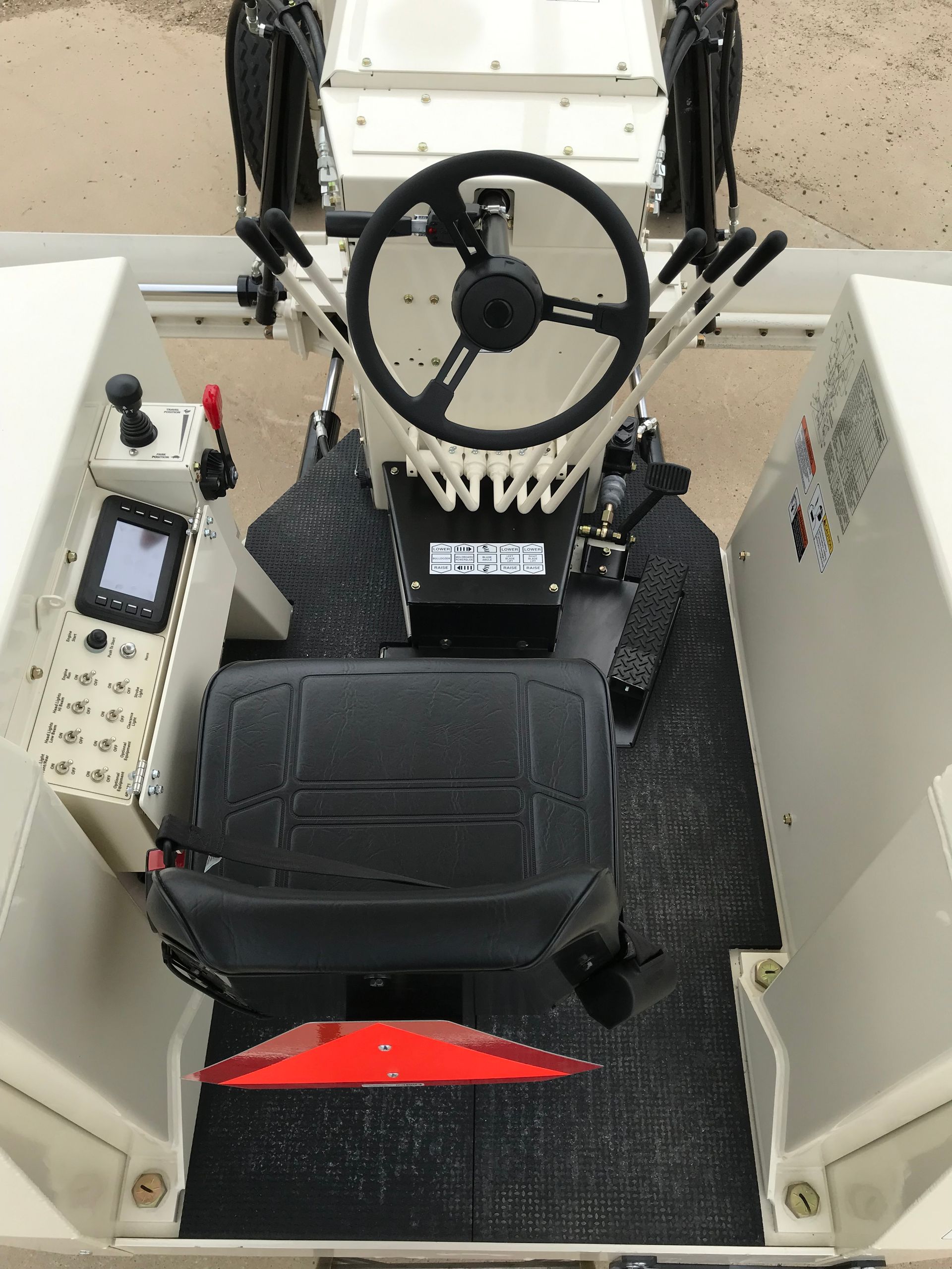 Overhead view of a construction vehicle's cockpit with steering wheel, seat, and control panel.