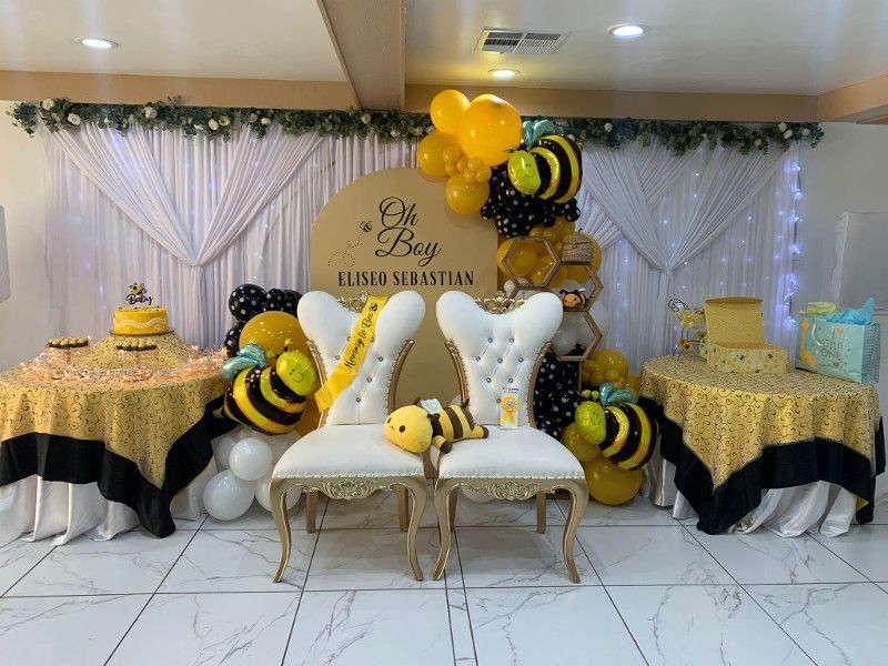 Baby shower with bee theme: yellow and black decor, chairs, balloons, and tables.