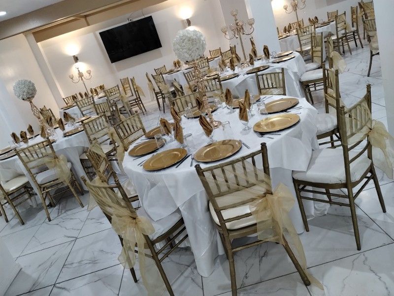 Elegant banquet hall with round tables set for dining, decorated with gold and white accents.