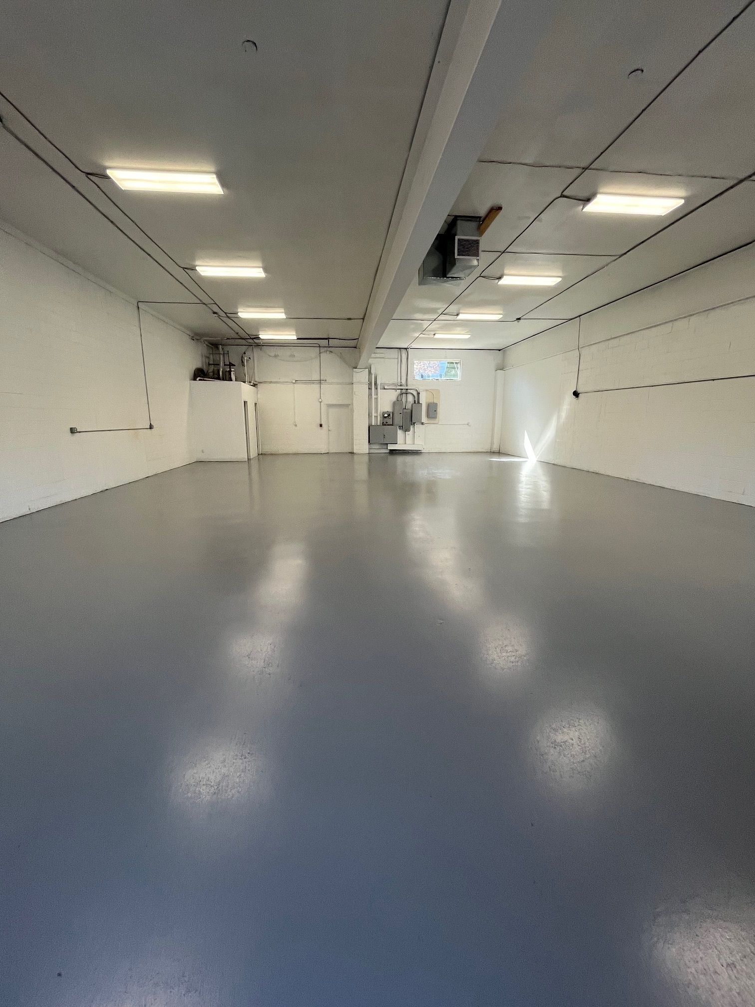 A large empty room with a blue floor and white walls.