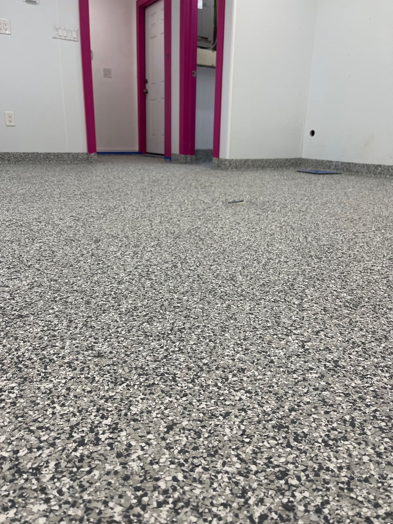 A room with a gray floor and pink doors