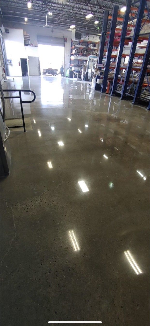 A large warehouse with lots of shelves and a shiny concrete floor.