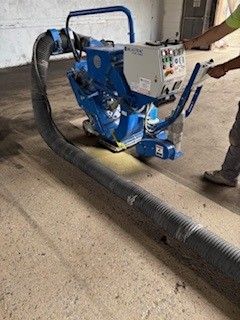 A person is using a machine to sand a concrete floor.