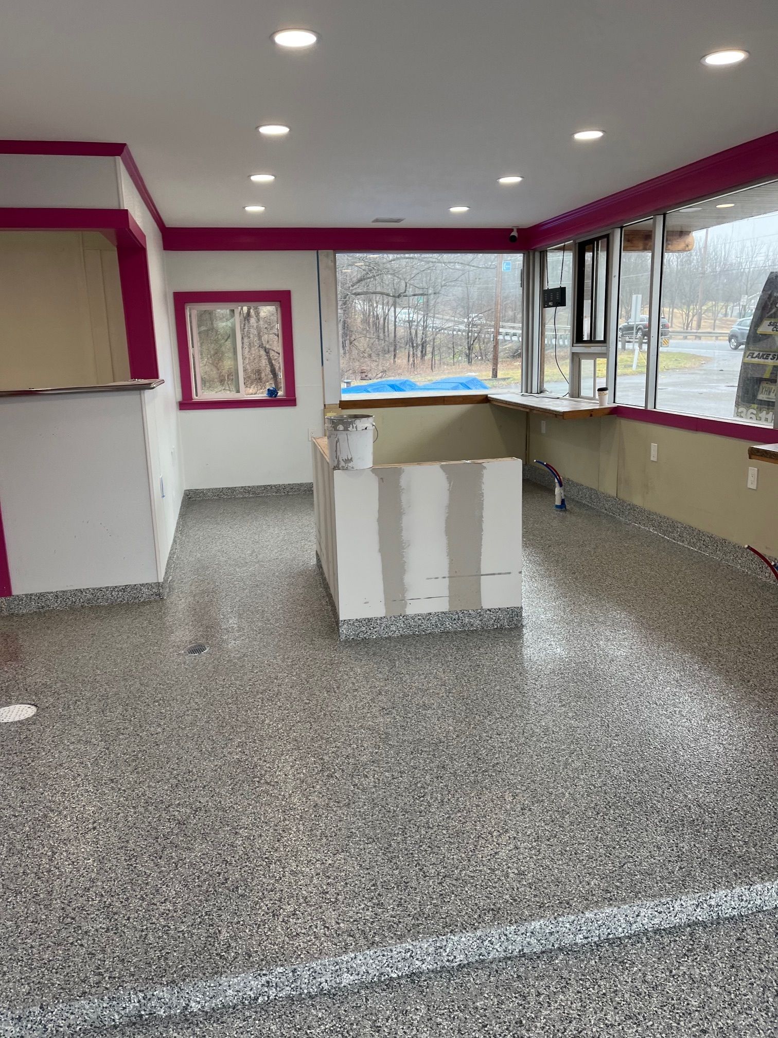 A large empty room with a concrete floor and a large window.