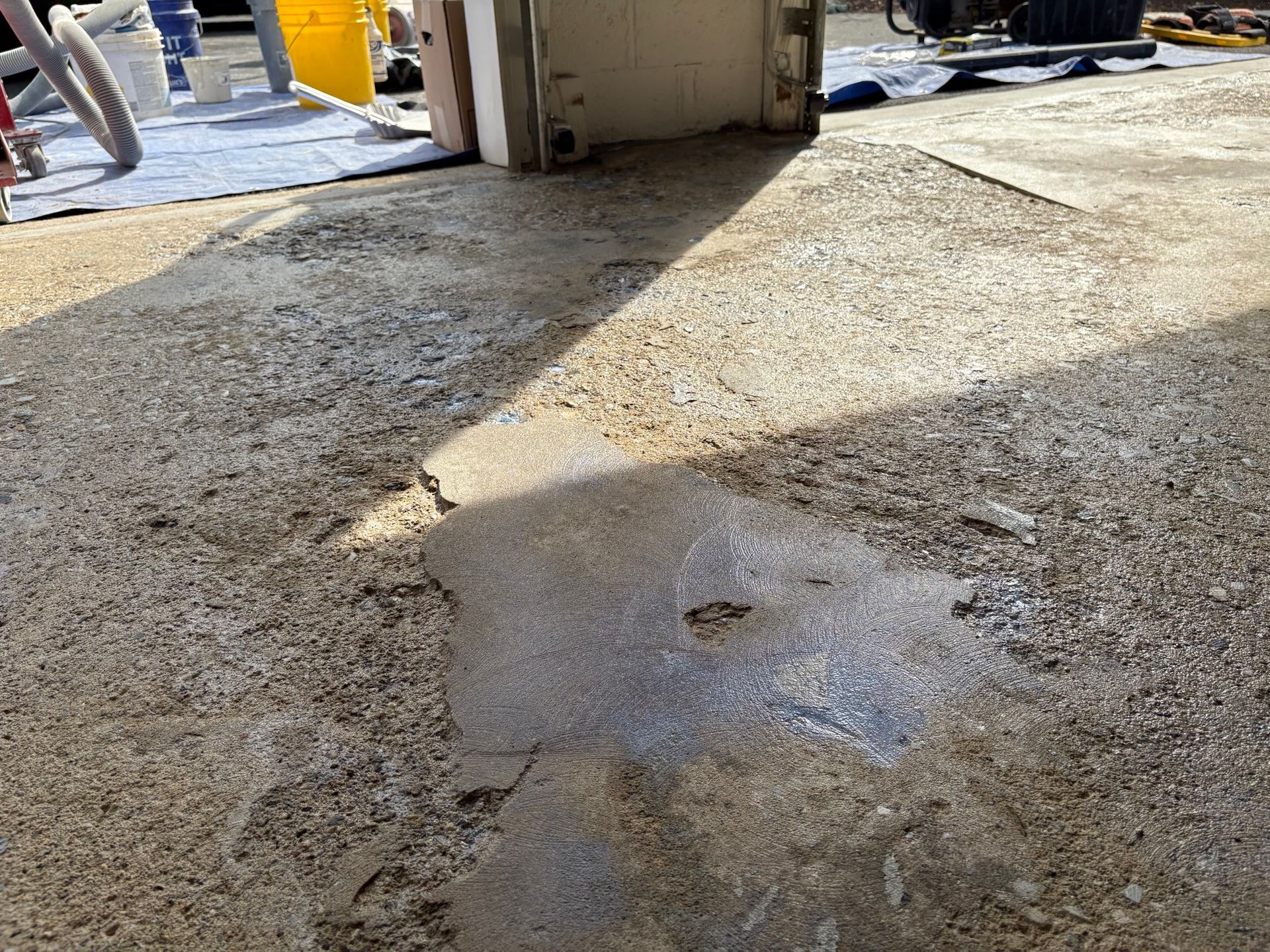 Uneven, weathered concrete surface with patch, possibly under repair; sunlight casts shadows.