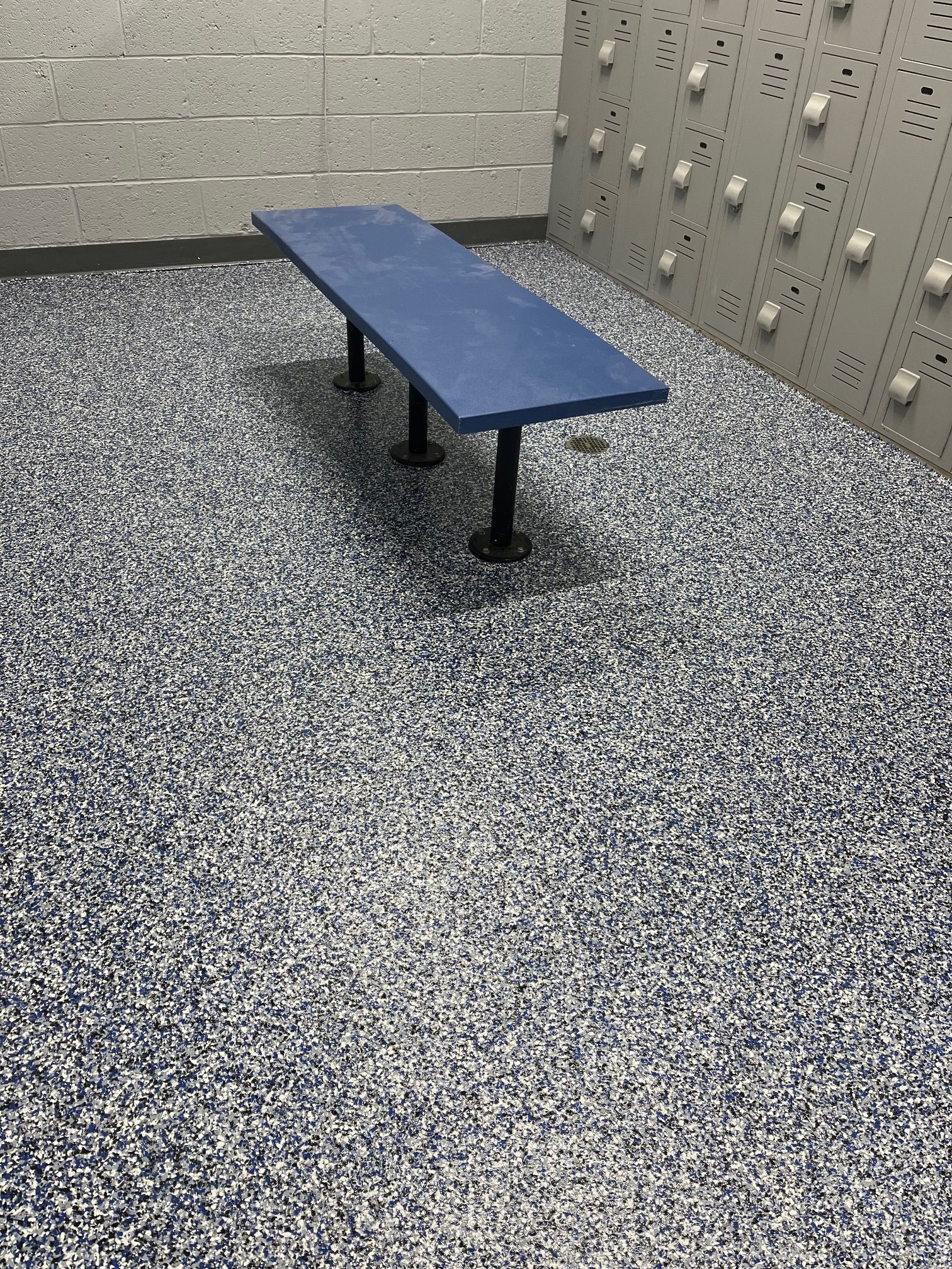 A blue bench is sitting in a room with lockers.