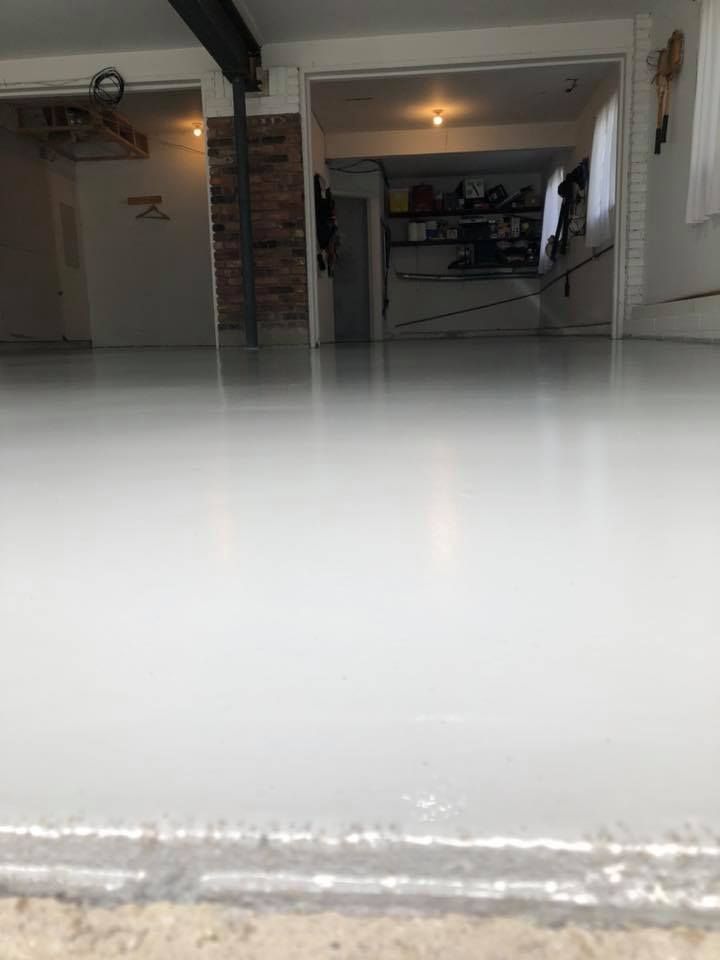 A white floor in a garage with a brick wall in the background.