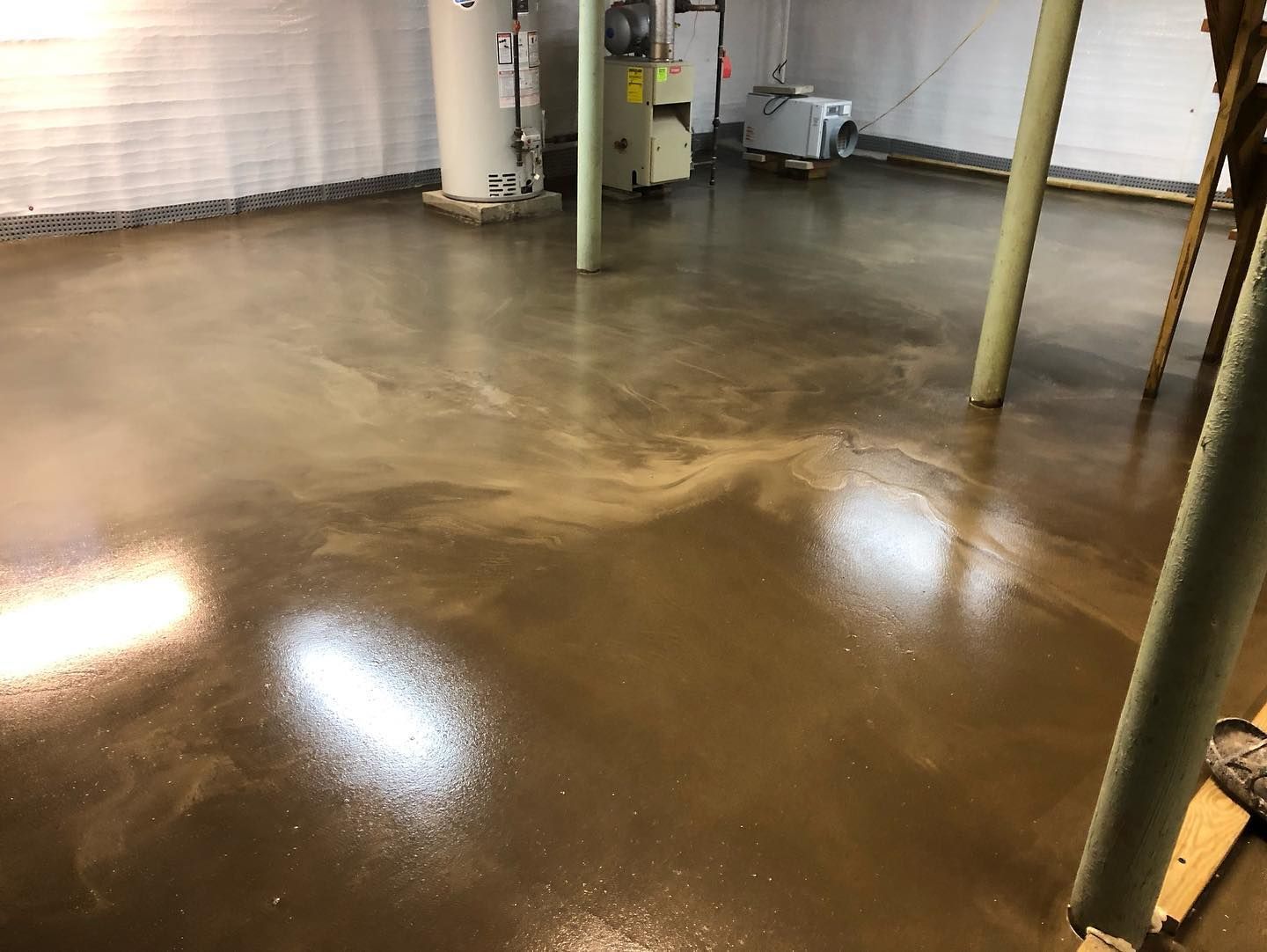 A concrete floor in a basement with a heater in the background.