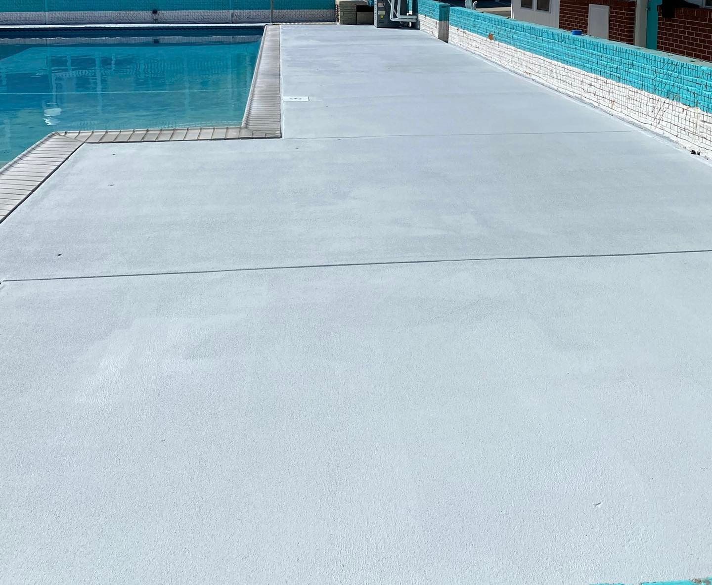 A concrete walkway leading to a swimming pool.