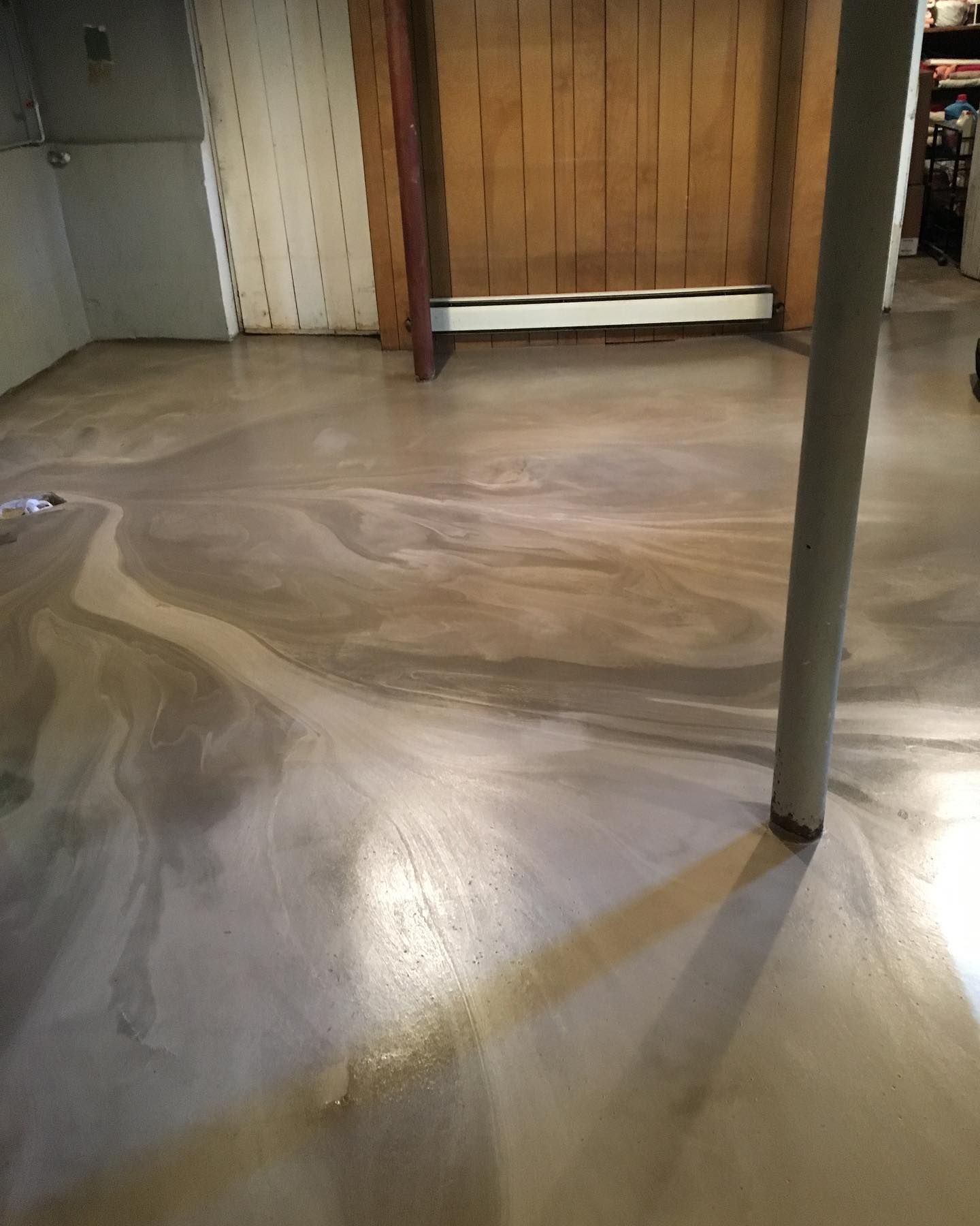 A basement with a concrete floor and a wooden wall.