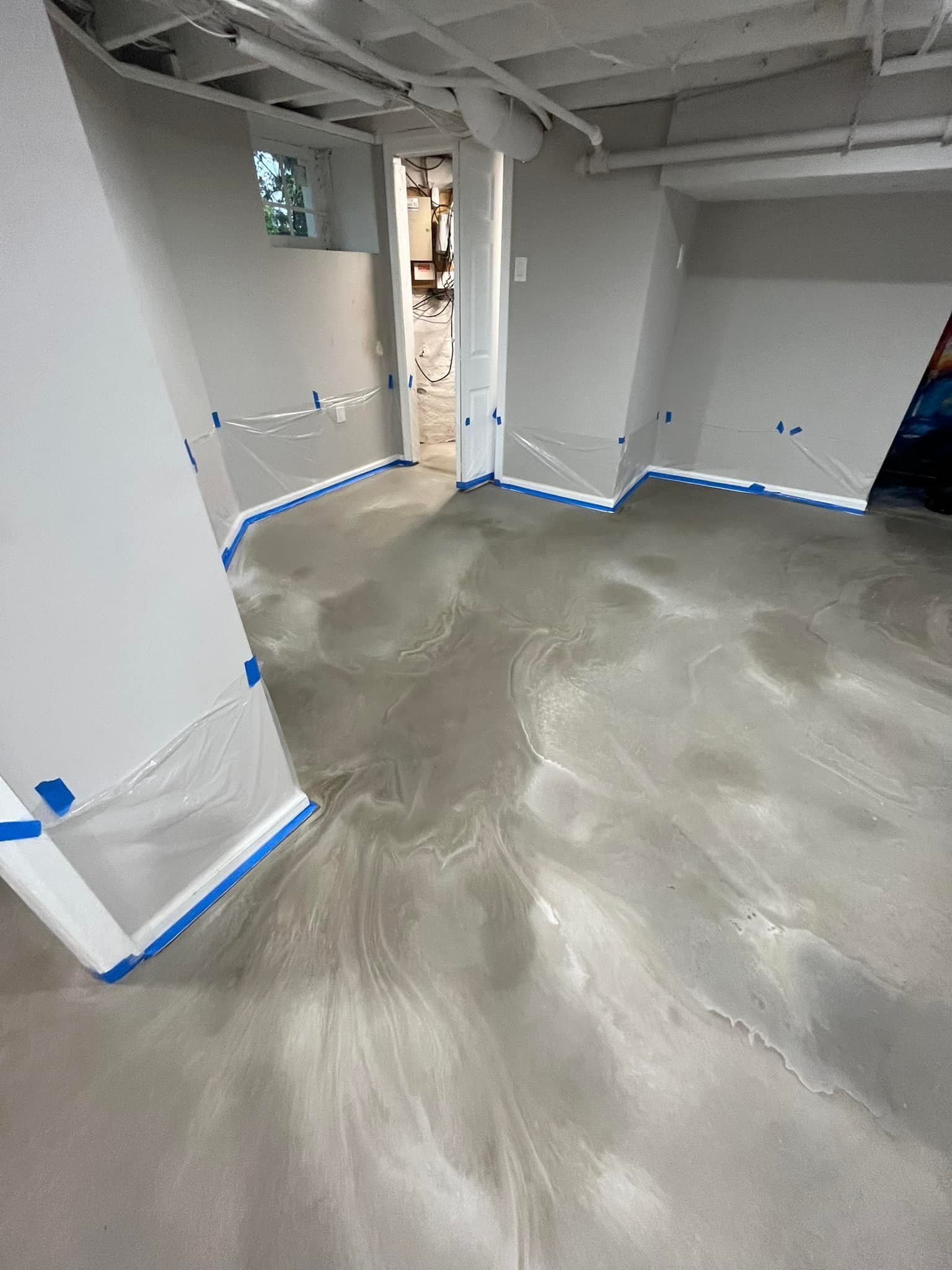 A concrete floor is being installed in a basement.
