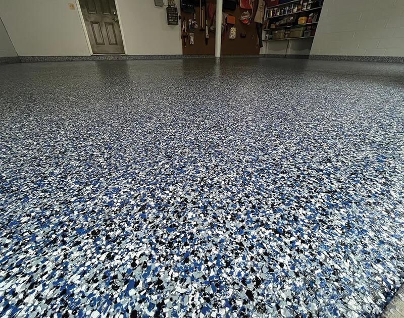 A garage floor with a lot of blue and white flakes on it.