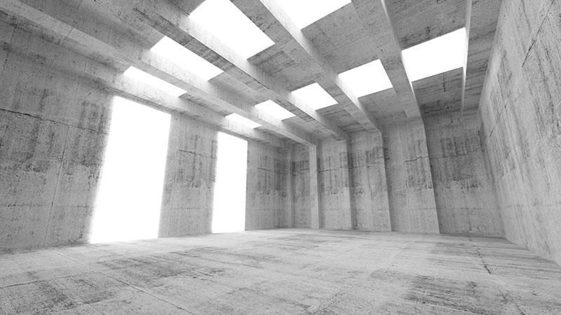 An empty concrete room with a lot of windows and a light coming through the ceiling.