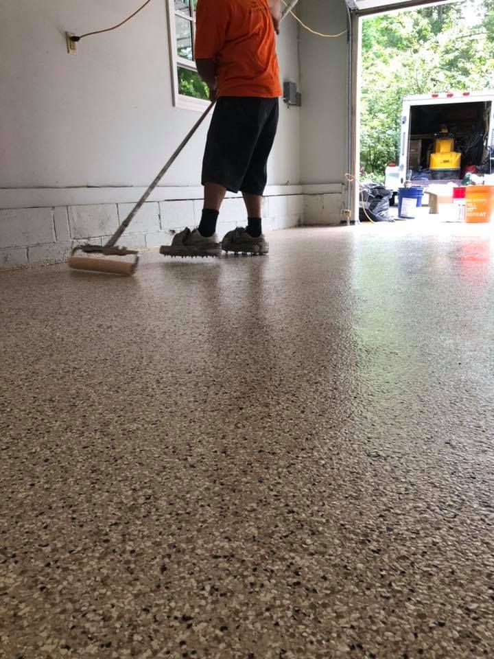 A man is cleaning a garage floor with a mop.