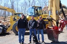 A man is standing on the back of a komatsu excavator.