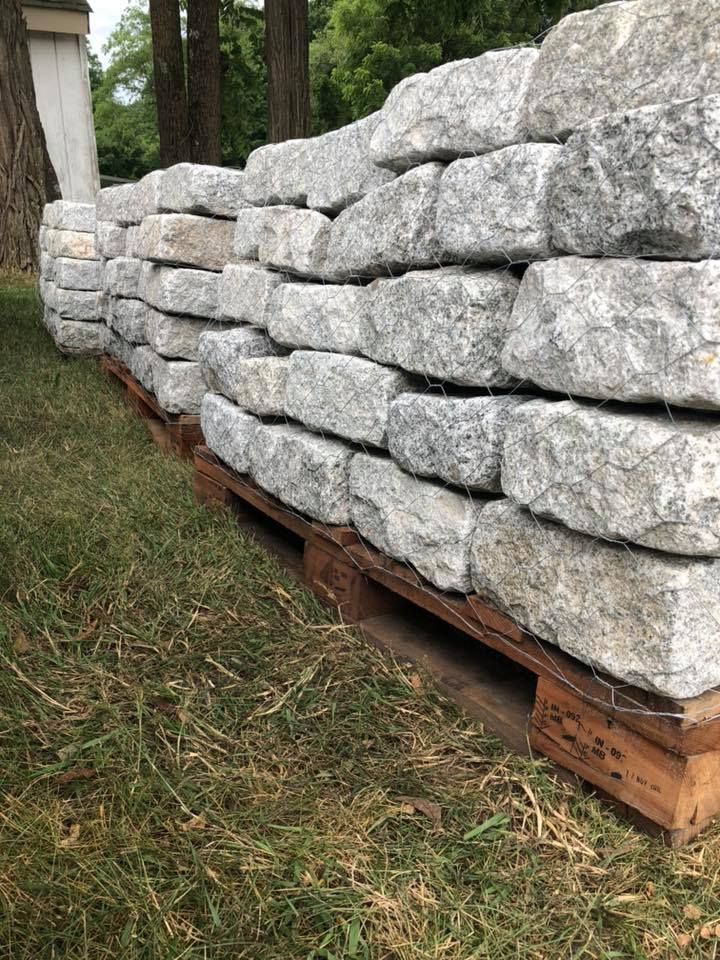 A pile of rocks sitting on top of wooden pallets in the grass.