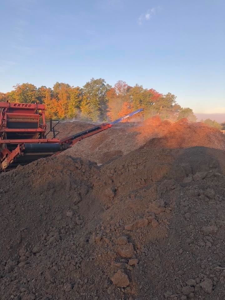 A pile of dirt is being processed by a machine in a field.