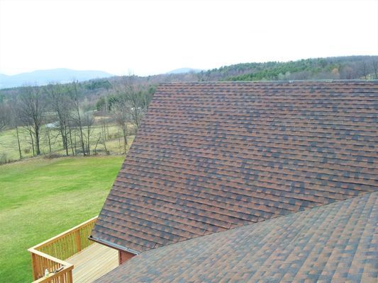 The roof of a house with a view of a field and mountains.