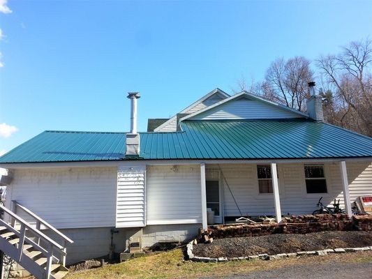 A white house with a green metal roof