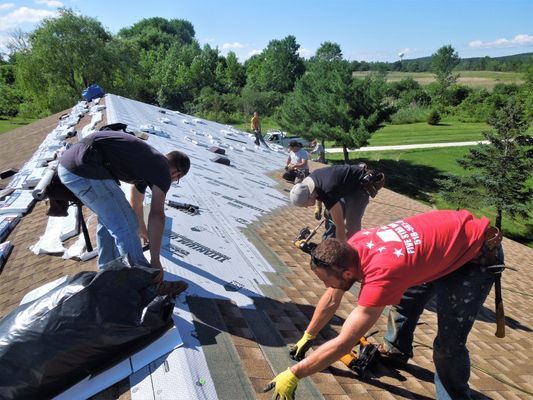 A man in a red shirt is working on a roof