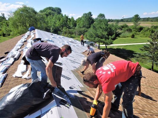 A man in a red shirt is working on a roof