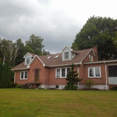 A brick house with a brown roof and white trim
