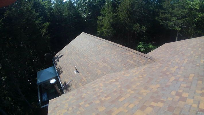 An aerial view of a roof of a house with trees in the background.