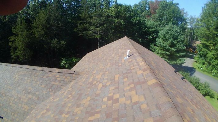 An aerial view of a house 's roof with trees in the background.