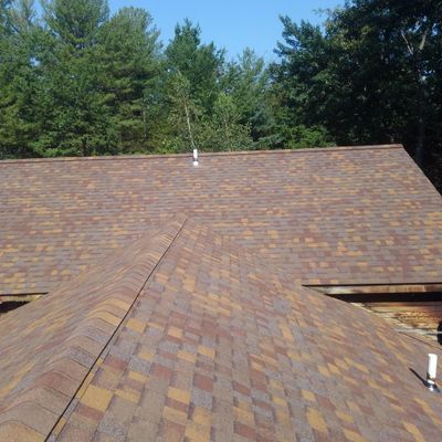 A roof with a lot of shingles and trees in the background