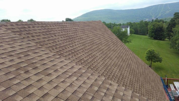 A roof with a view of a field and mountains in the background.