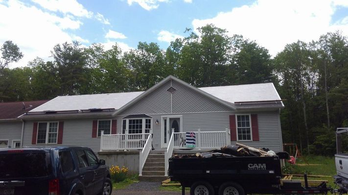 A truck and trailer are parked in front of a house.