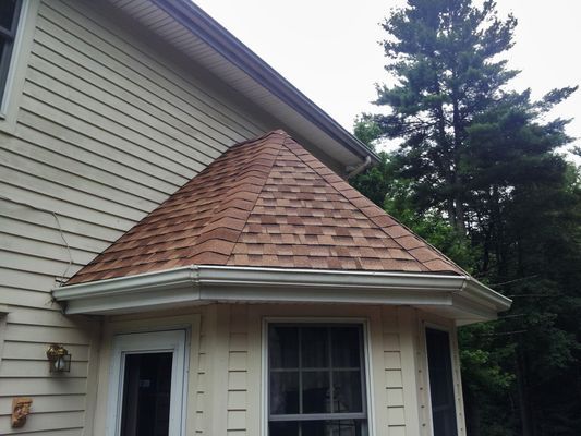 A white house with a brown roof and a bay window