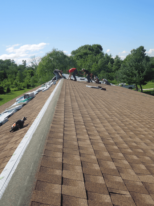 A group of people are working on the roof of a house