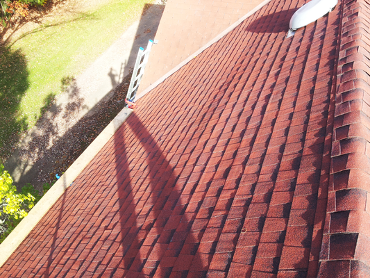 An aerial view of a red roof with a ladder attached to it