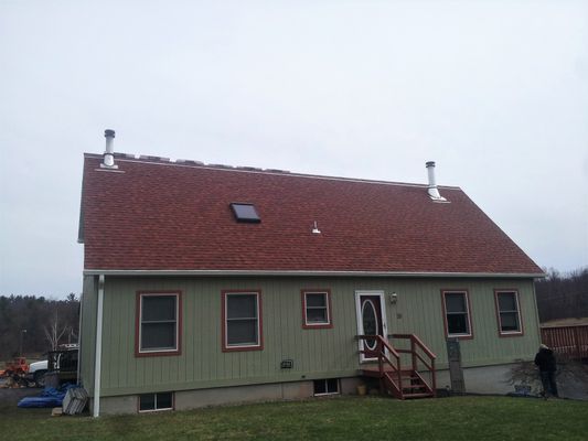 A green house with a red roof and stairs