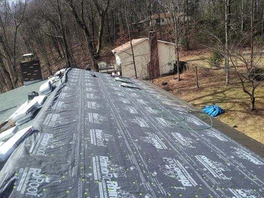 The roof of a house is being covered with a black tarp.