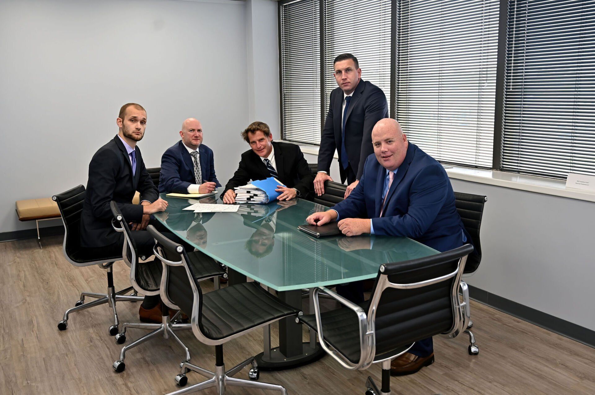 a group of men in suits are sitting around a conference table.