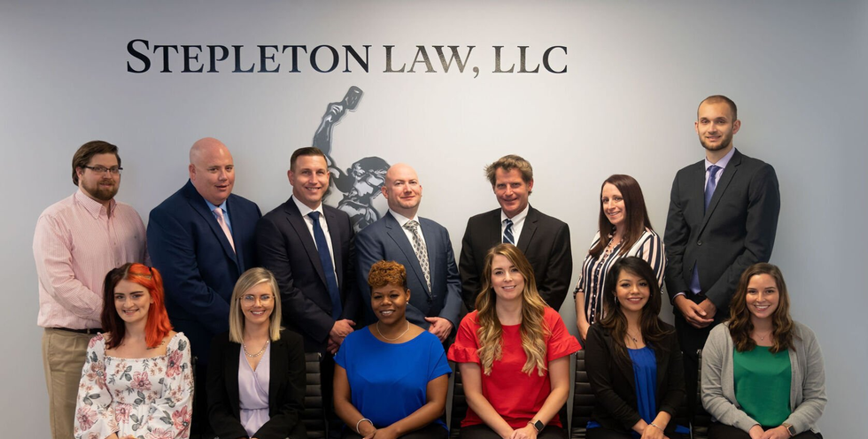 a group of people are posing for a picture in front of a sign that says stepleton law llc .