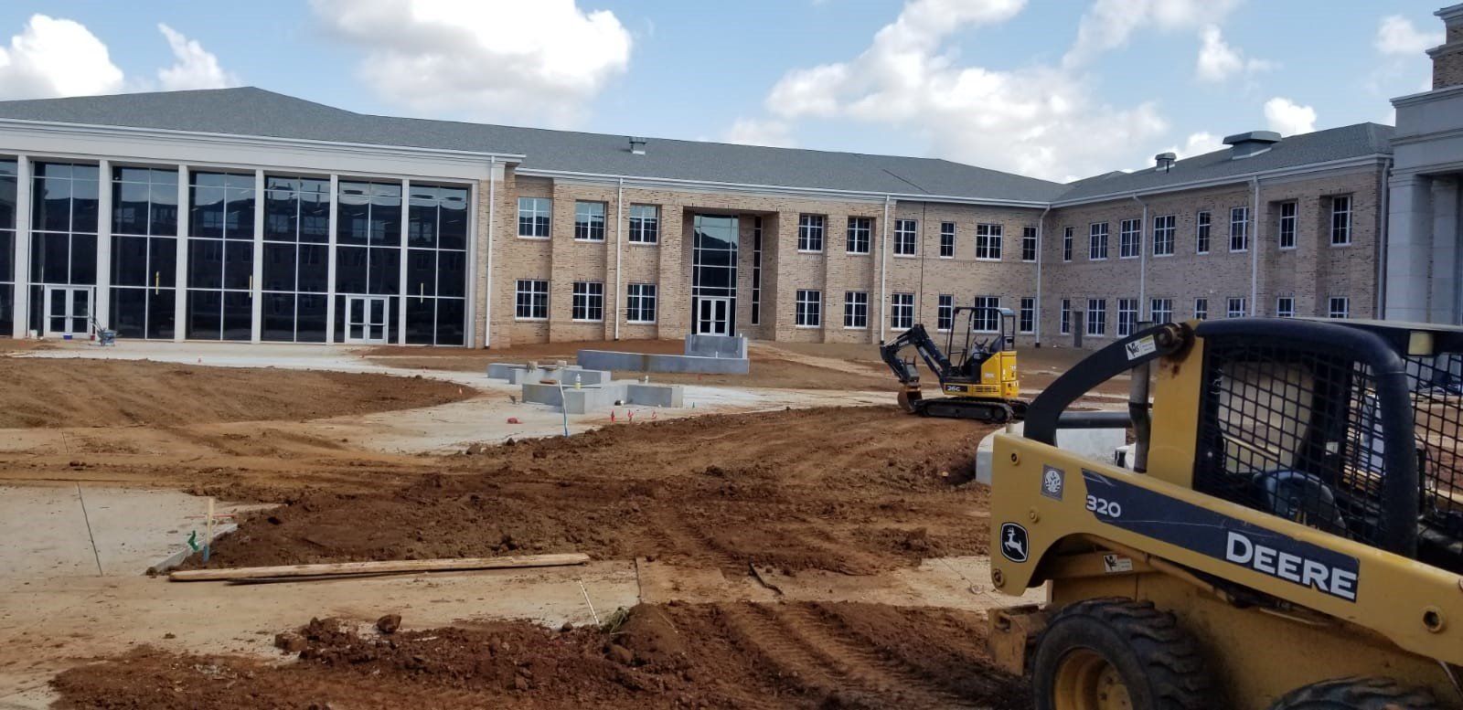 A bulldozer is moving dirt in front of a large building.