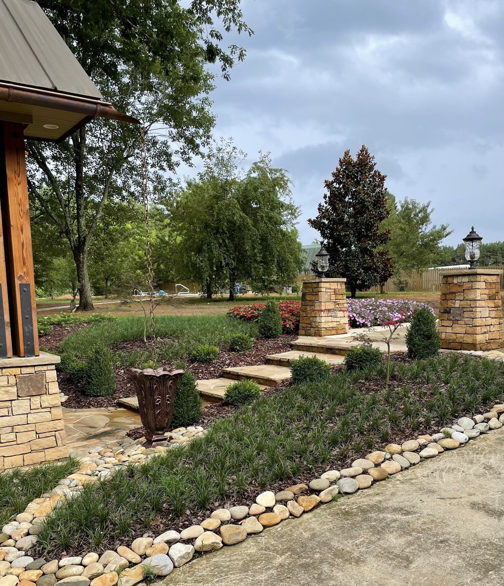 A lush green garden with a stone walkway leading to a house.