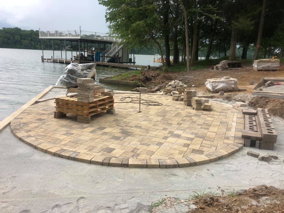 A brick patio is being built next to a body of water.