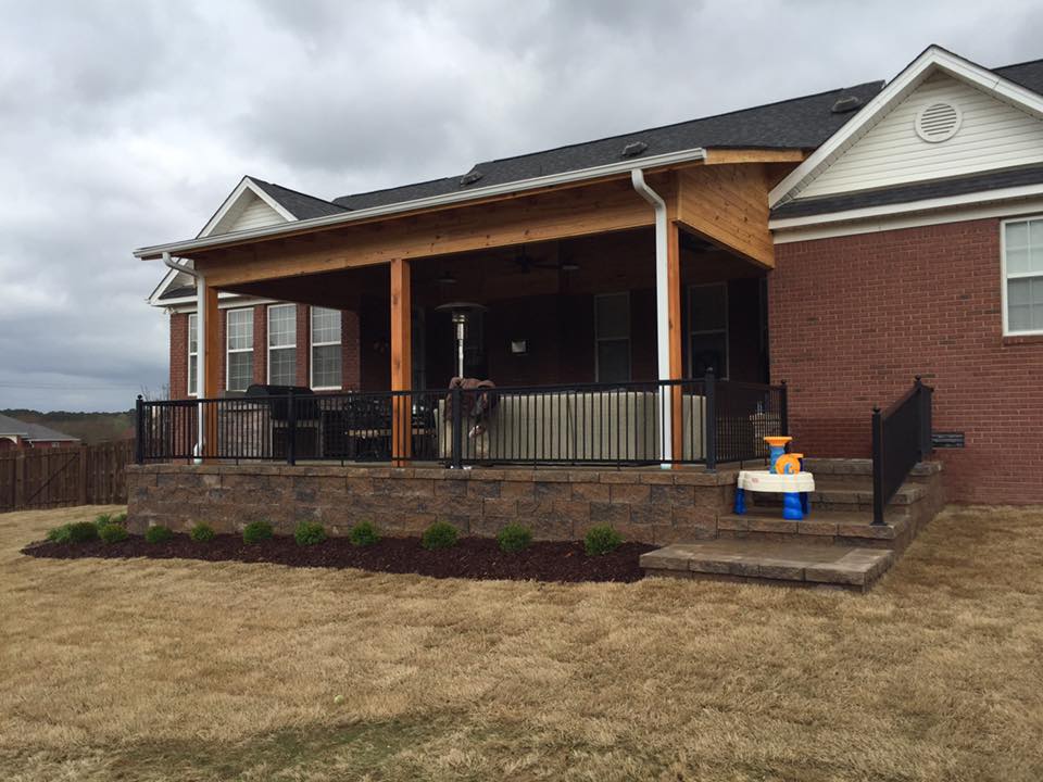 A large brick house with a covered porch and stairs leading up to it.