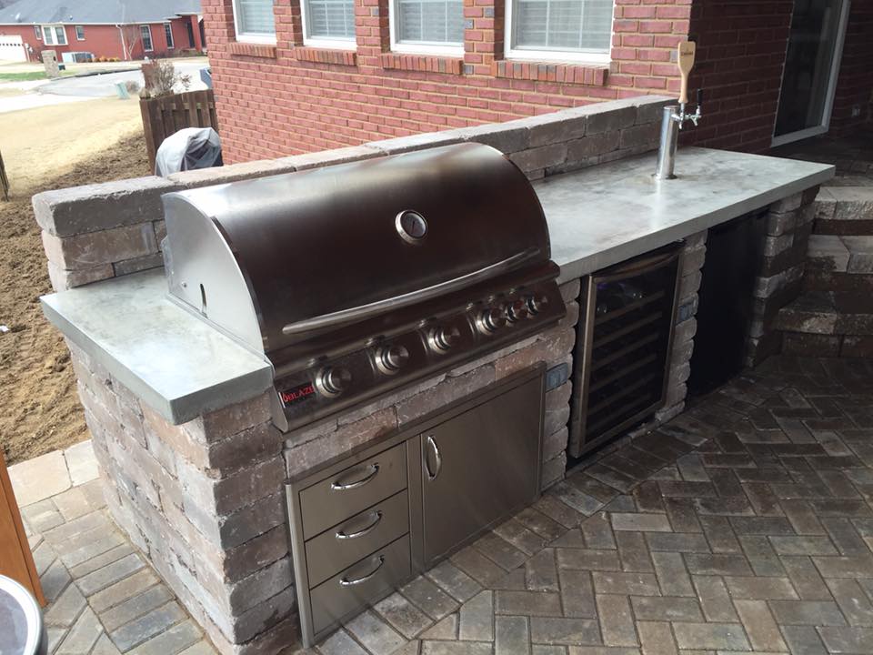 A grill is sitting on top of a brick counter next to a brick building.