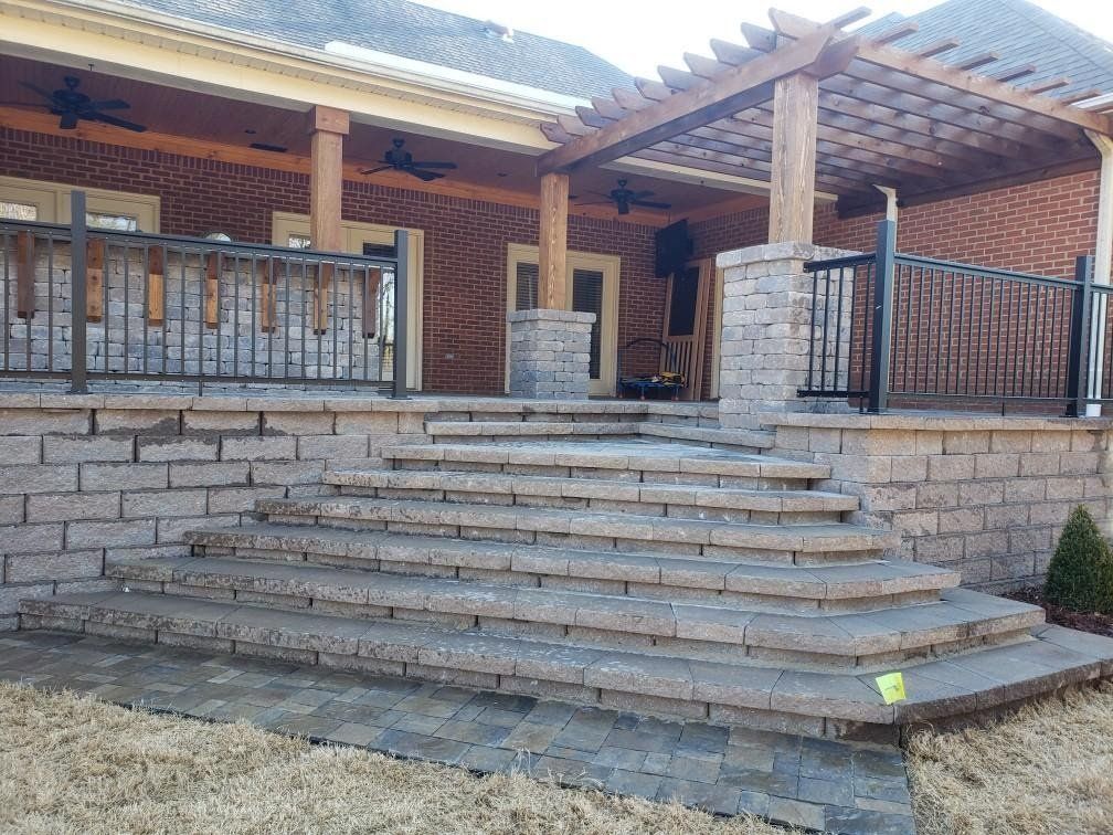 A brick wall with stairs leading up to a covered porch