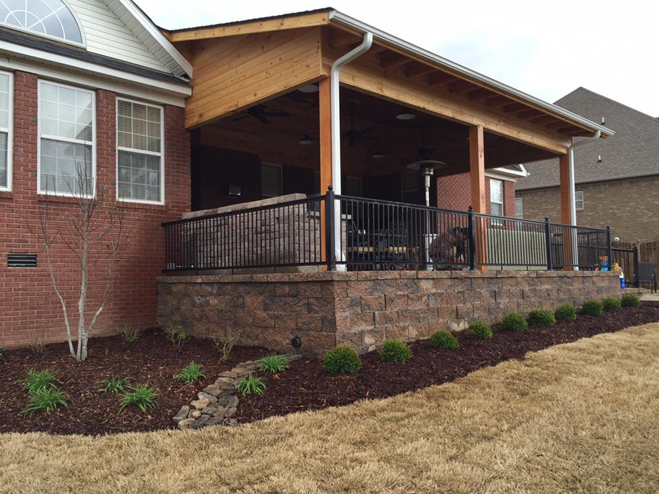 A house with a covered porch and a brick wall surrounding it.