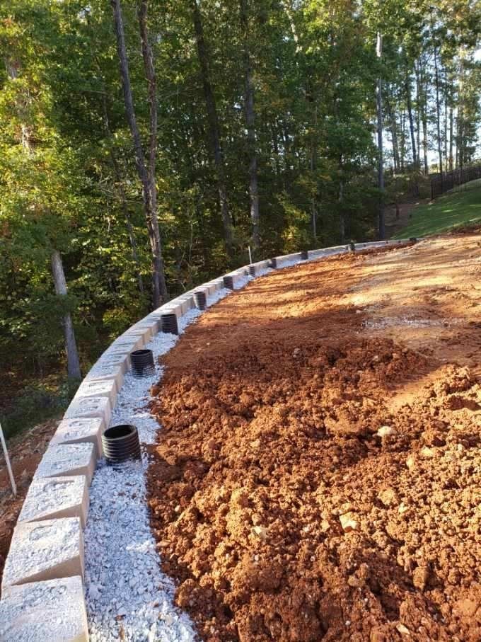 A pile of dirt is sitting next to a stone wall.