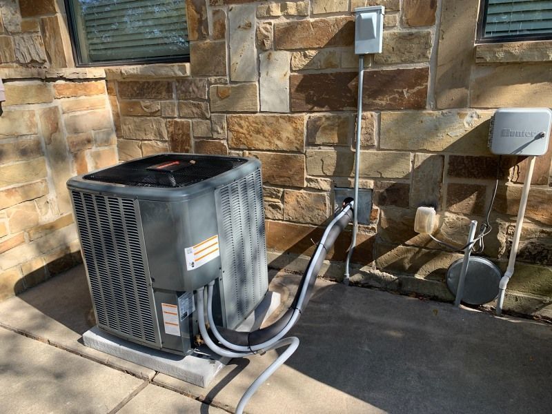 An air conditioner is sitting outside of a brick building.