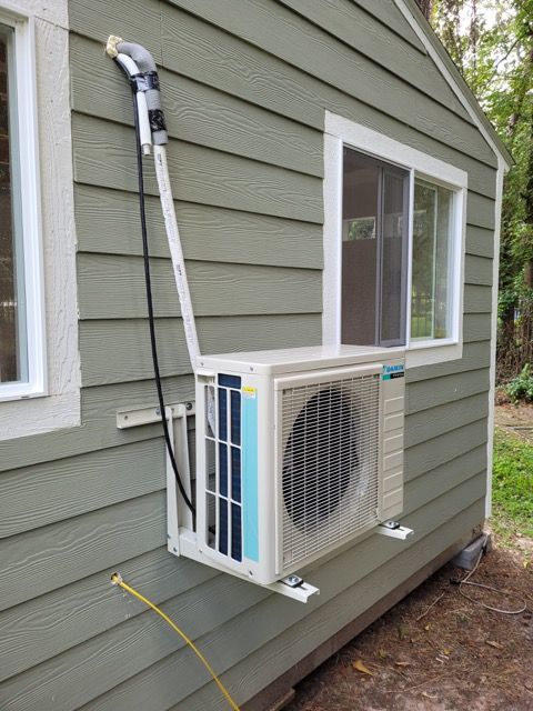 A hose is attached to the side of a house next to a window.