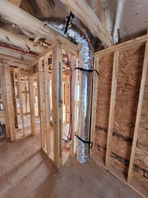 A room under construction with a duct hanging from the ceiling