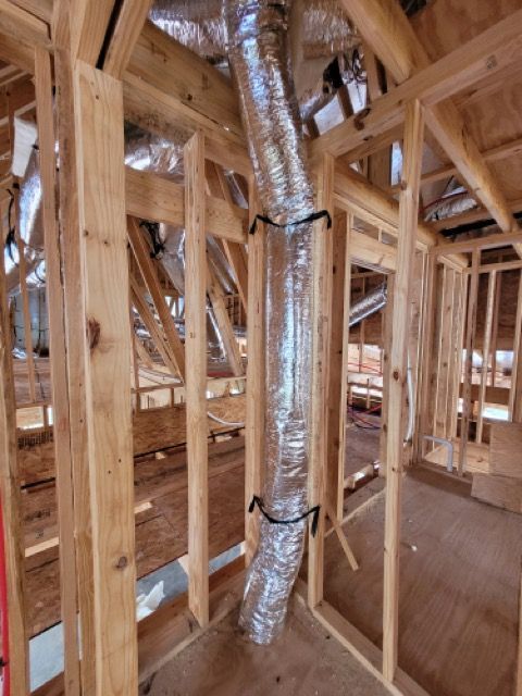 A wooden frame of a house with a metal pipe coming out of it